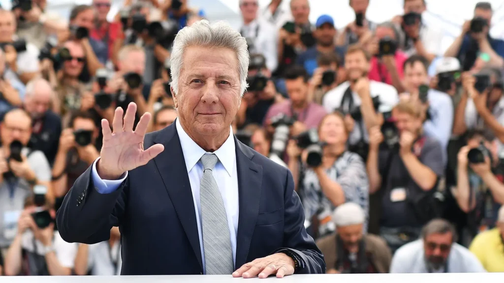Dustin Hoffman smiling in a formal suit at a Hollywood event, showcasing his signature charisma.
