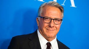 Dustin Hoffman smiling in a formal suit at a Hollywood event, showcasing his signature charisma.
