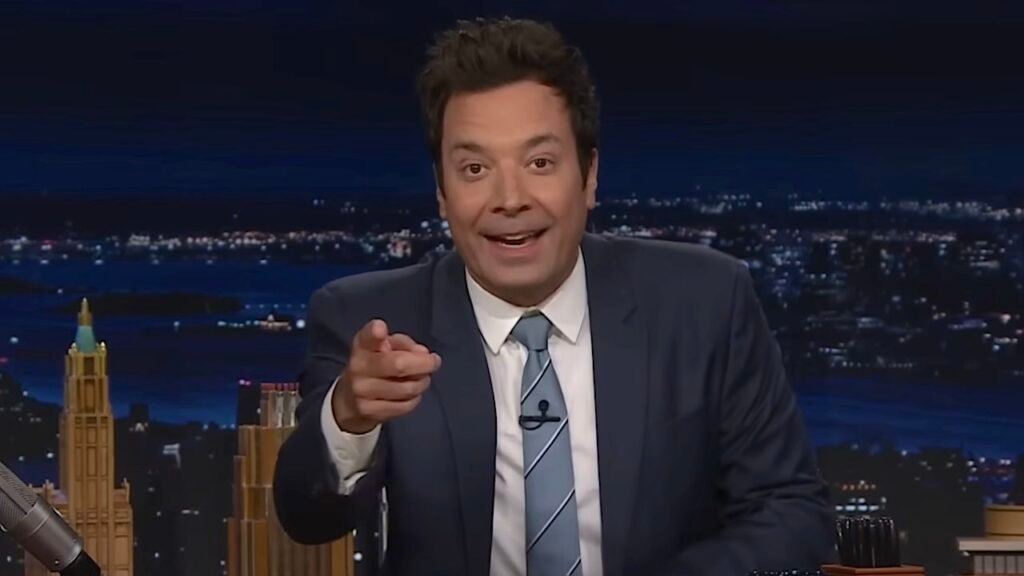 Jimmy Fallon hosting The Tonight Show with celebrity guests, performing comedy sketches, games, and viral segments in a modern late-night TV studio